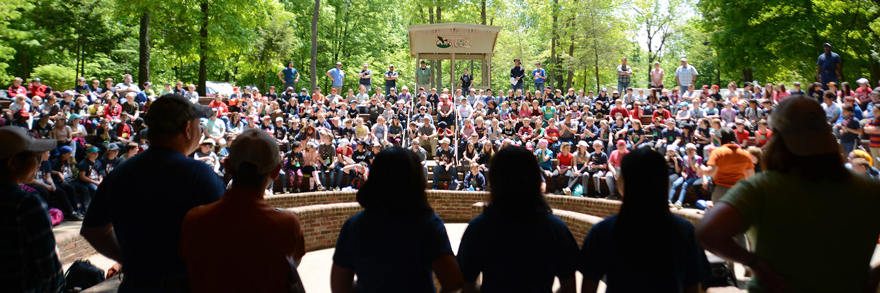 Staff members stand in front of a crowd of students at the amphitheater.